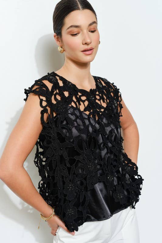 Black floral cutout lace top with pearl embellishments styled with white pants