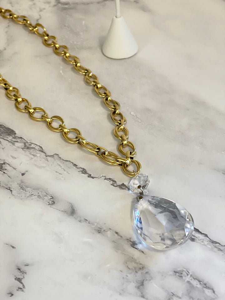 Close-up of faceted vintage chandelier crystal pendant on gold link necklace
