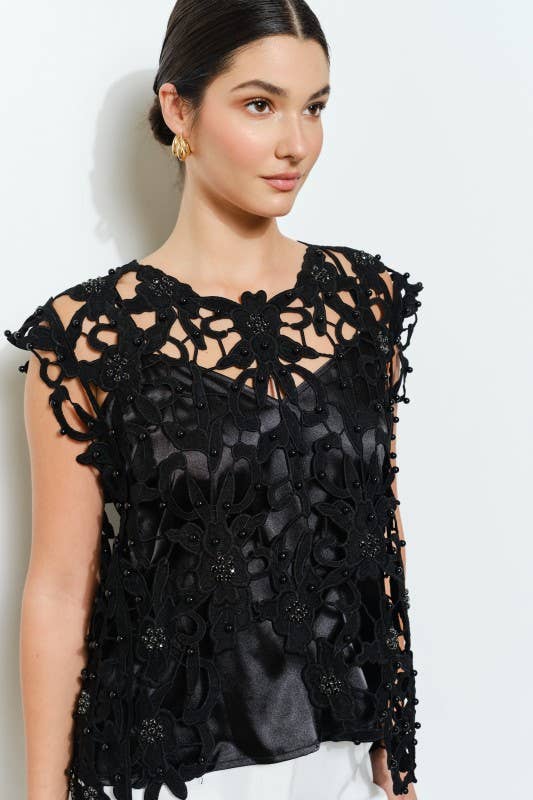 Close-up of black floral cutout lace top with pearl and rhinestone details