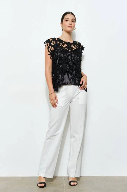 Black embellished floral lace top styled with white pants, full-length view