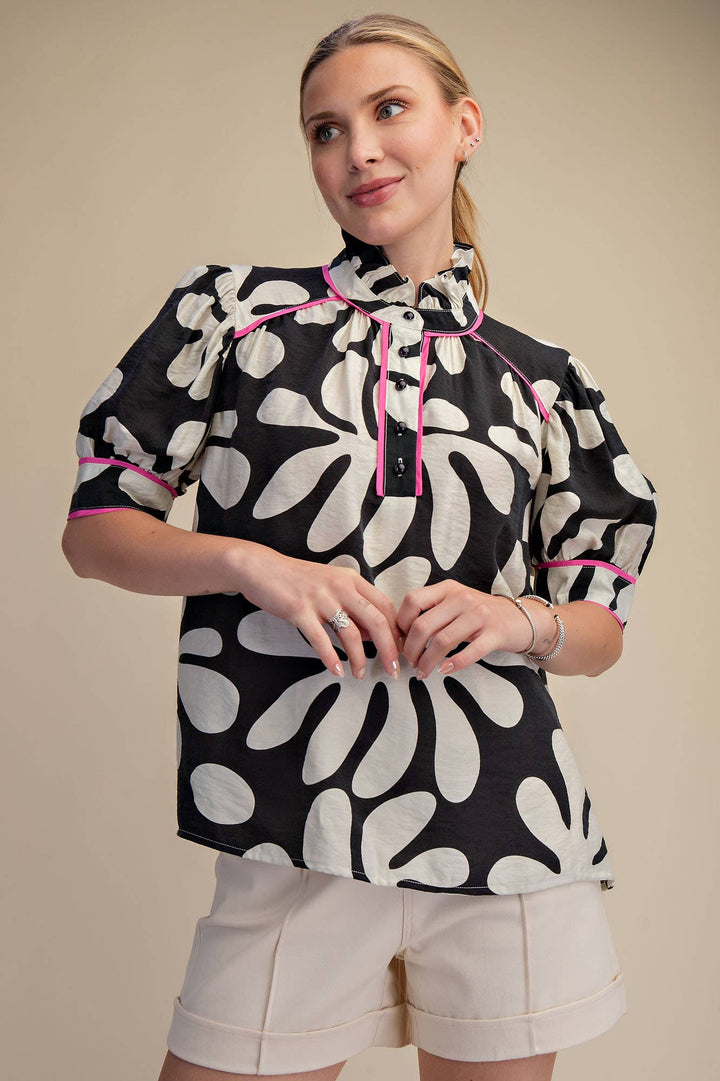 Black and ivory abstract floral blouse with hot pink piping, ruffled high neckline and short puff sleeves, front view