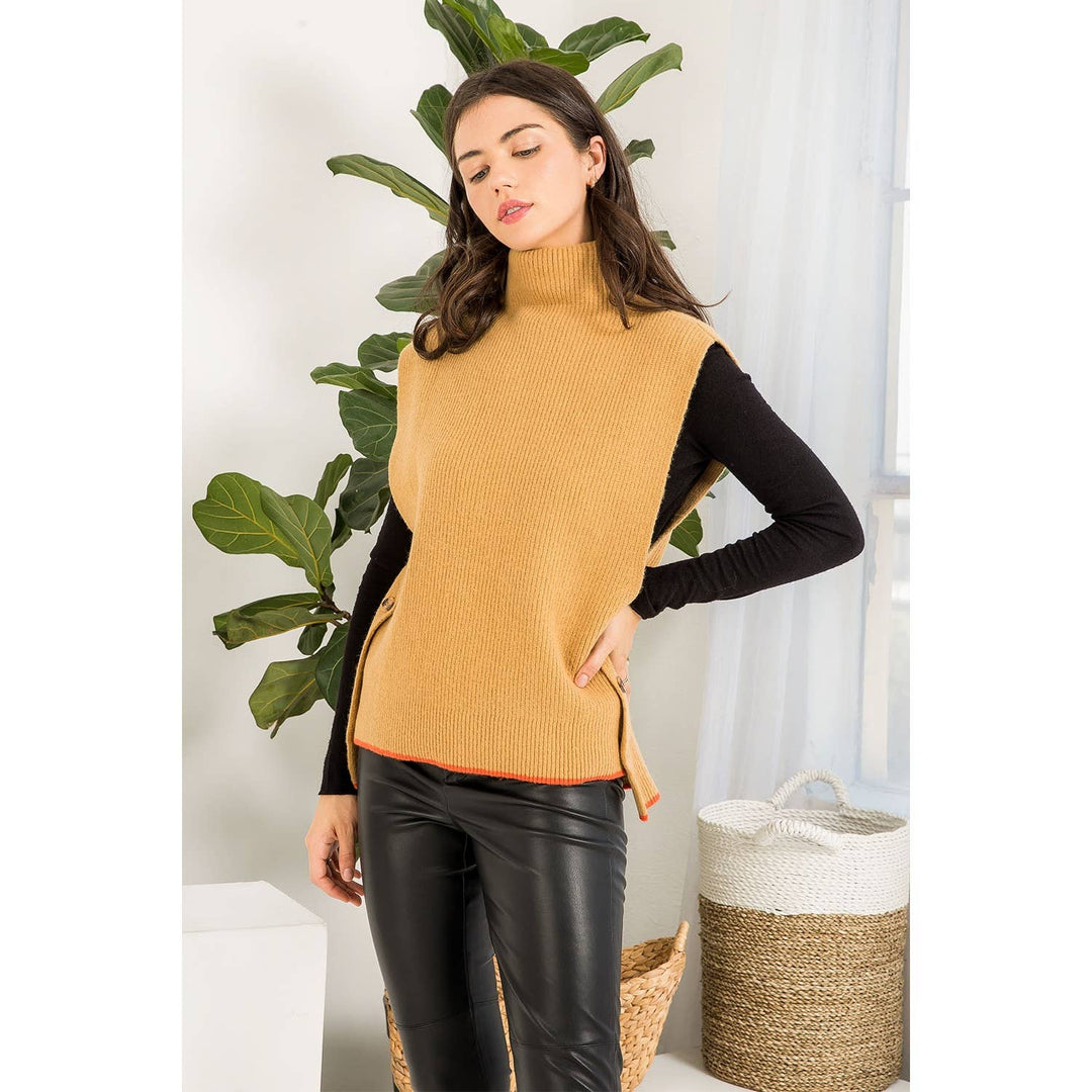 Contrast Theory camel sweater vest with mock neck, side buttons and orange contrast trim layered over a black long sleeve top.