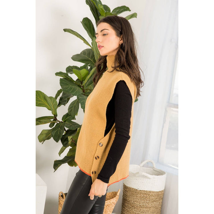 Side view of camel sweater vest showing open sides, decorative buttons and orange contrast hem.