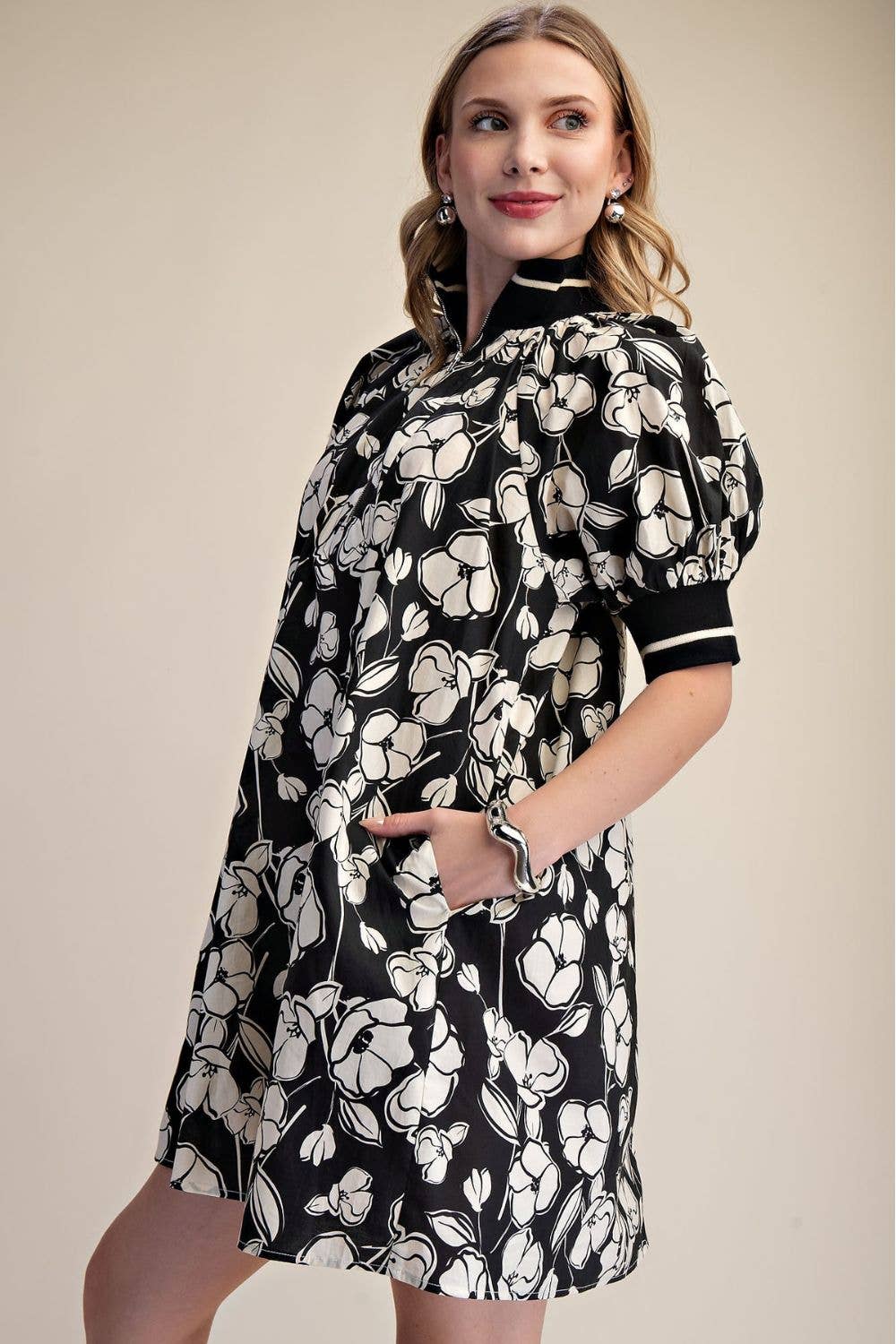 Side view of black and ivory floral mini dress showing puff sleeves, contrast cuffs and side pocket