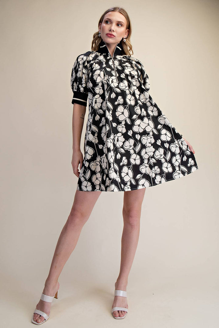 Full-length view of black and ivory floral mini dress with quarter-zip collar, puff sleeves and A-line silhouette