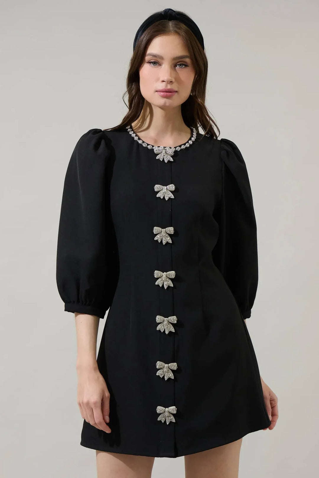 Black mini dress with rhinestone bow accents and crystal trimmed neckline