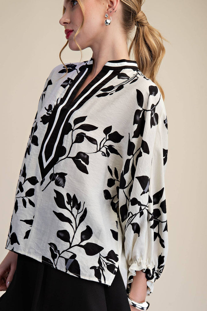 Side view of black and ivory botanical blouse showing relaxed fit and gathered ruffle cuff