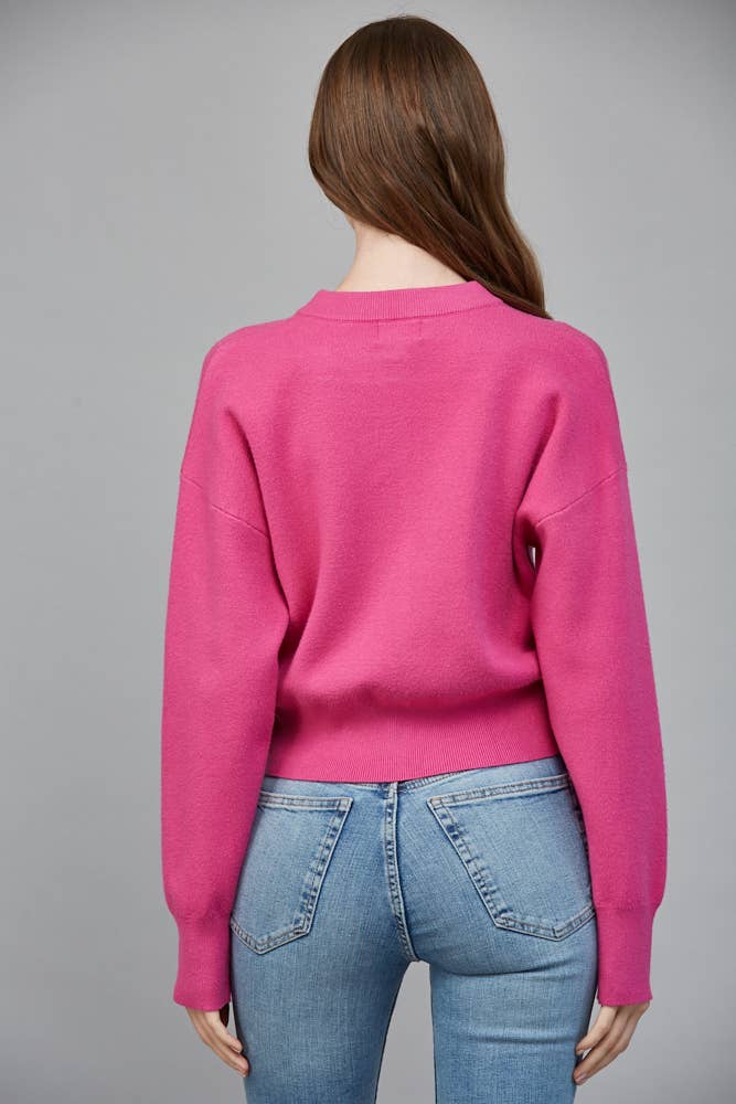 Back view of bright pink cardigan showing the relaxed fit, dropped shoulders and ribbed waistband.