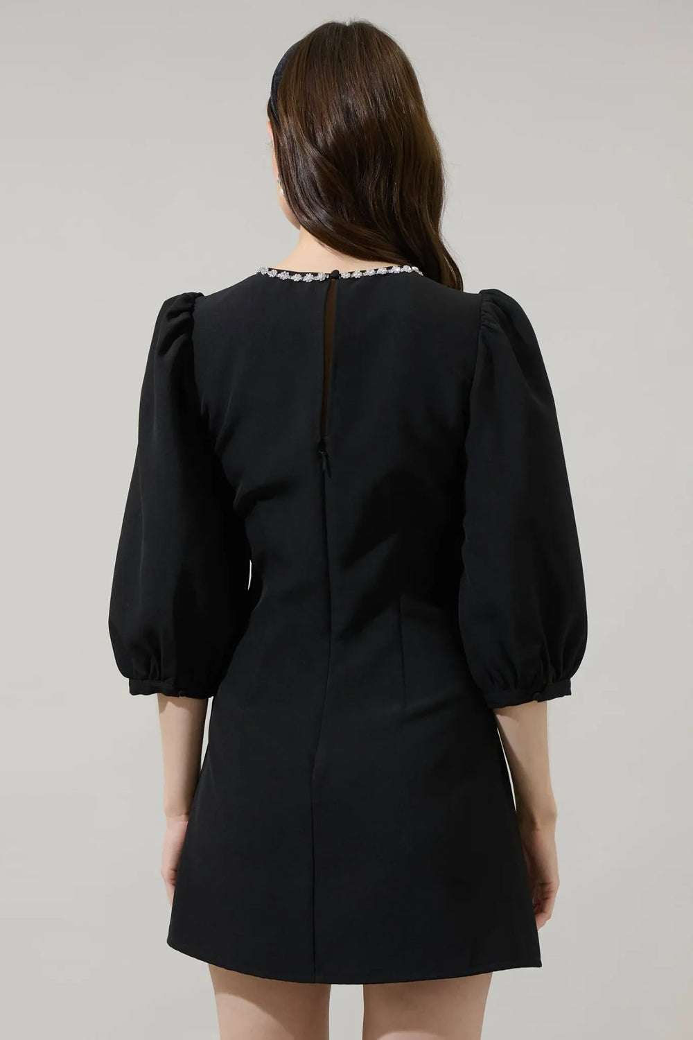 Back view of black A-line mini dress with puff sleeves and keyhole closure