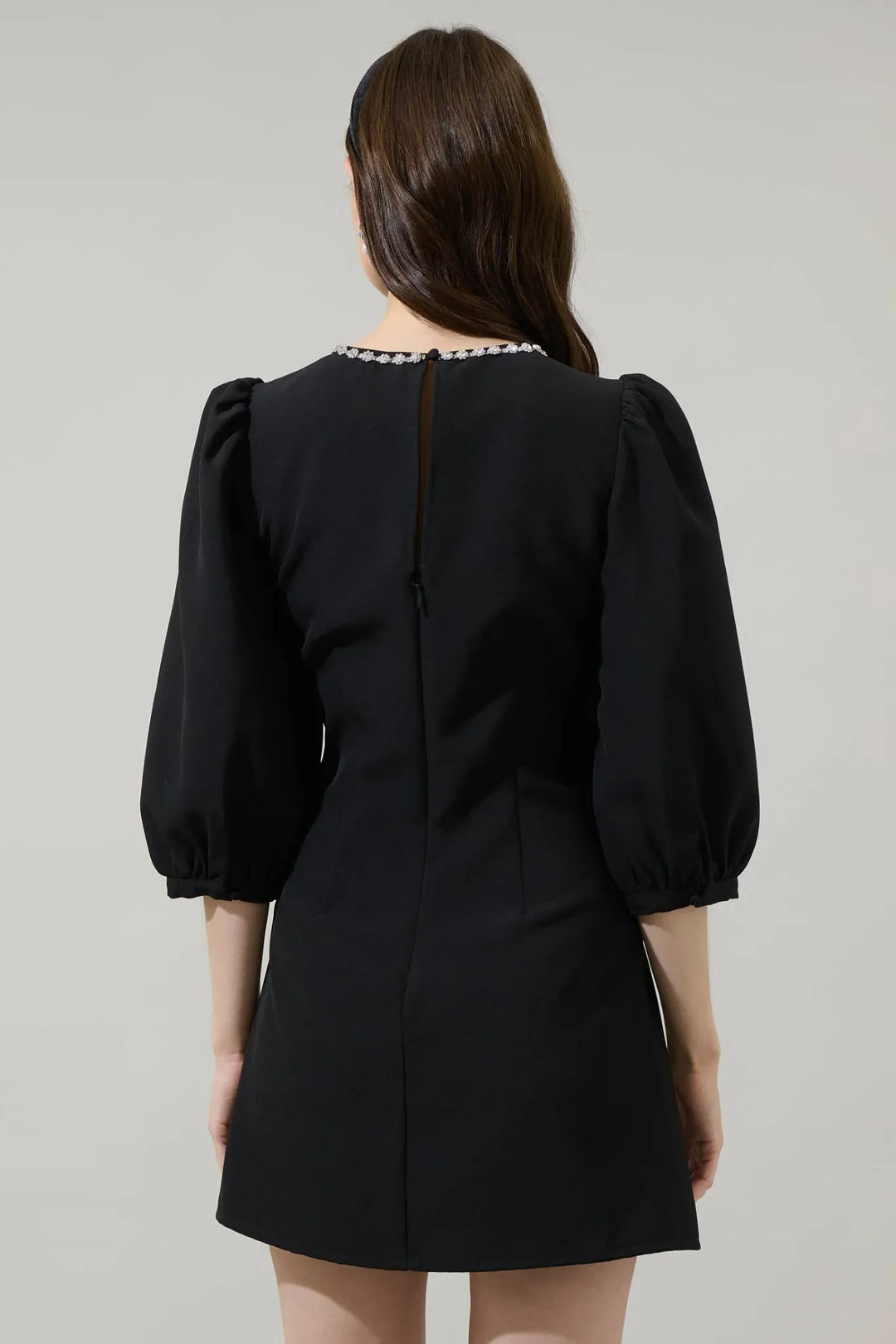 Back view of black A-line mini dress with puff sleeves and keyhole closure