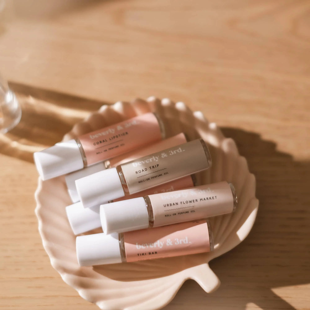 Beverly & 3rd roll-on perfume oils displayed together in a shell dish, featuring a variety of fragrances in 10ml bottles.