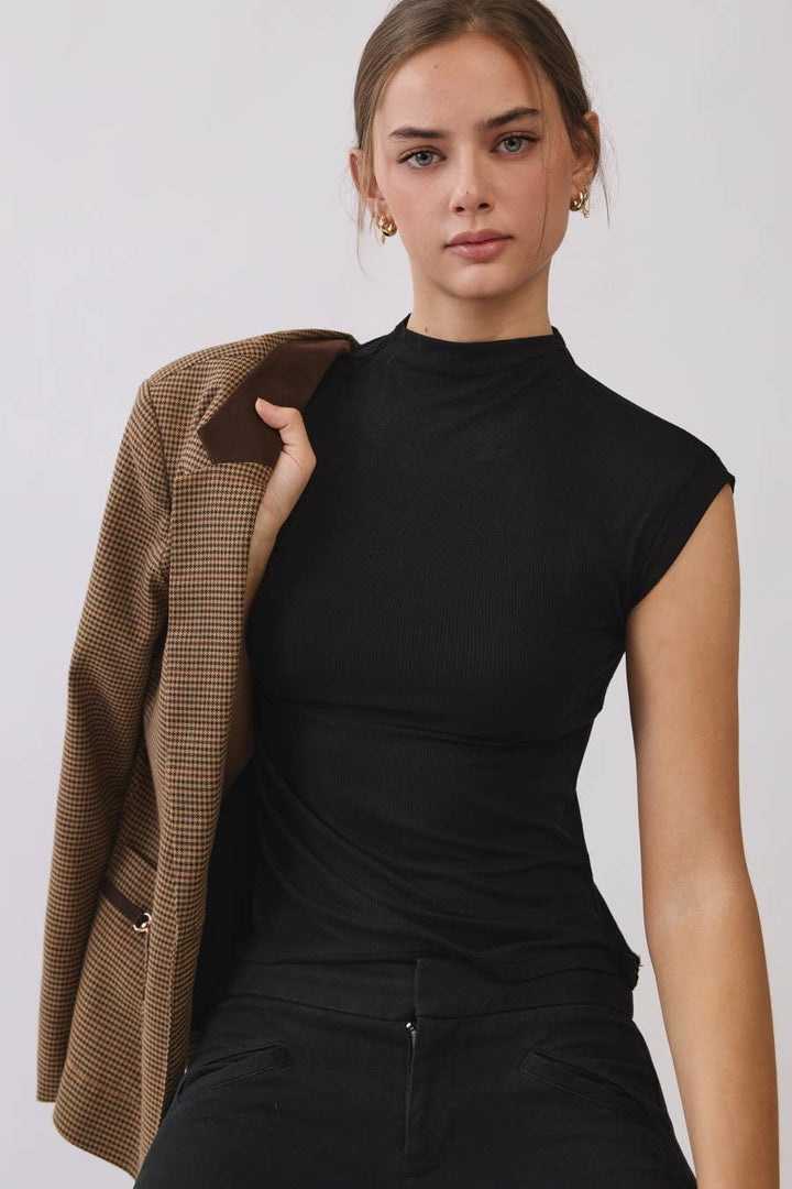 Women's black ribbed mock neck sleeveless top with cap sleeves, styled with black pants.