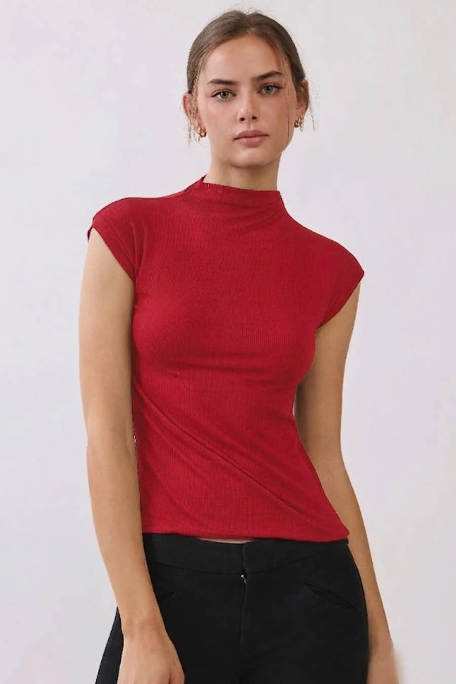 Women's red ribbed mock neck sleeveless top with cap sleeves and a fitted silhouette, styled with black pants.
