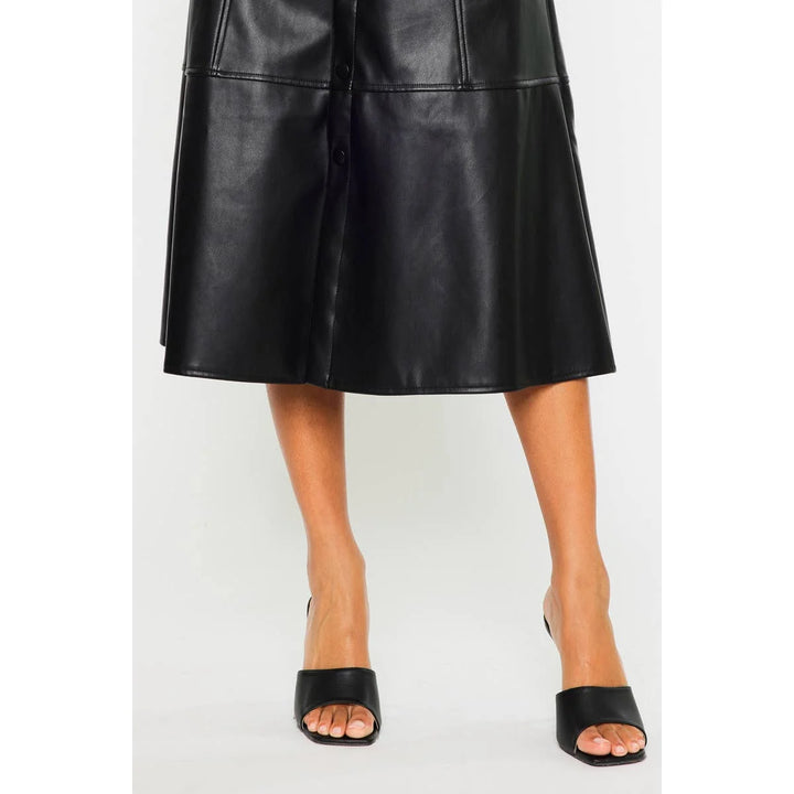Close-up of Rebel Luxe black faux leather midi skirt showing smooth leather-look texture, panel seams and front snap buttons