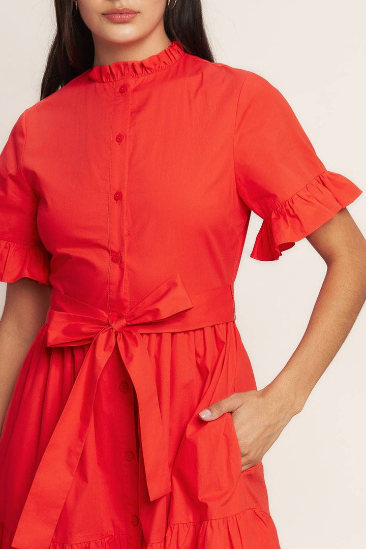 Close up of orange red dress with ruffle neckline, button front, sash and pocket